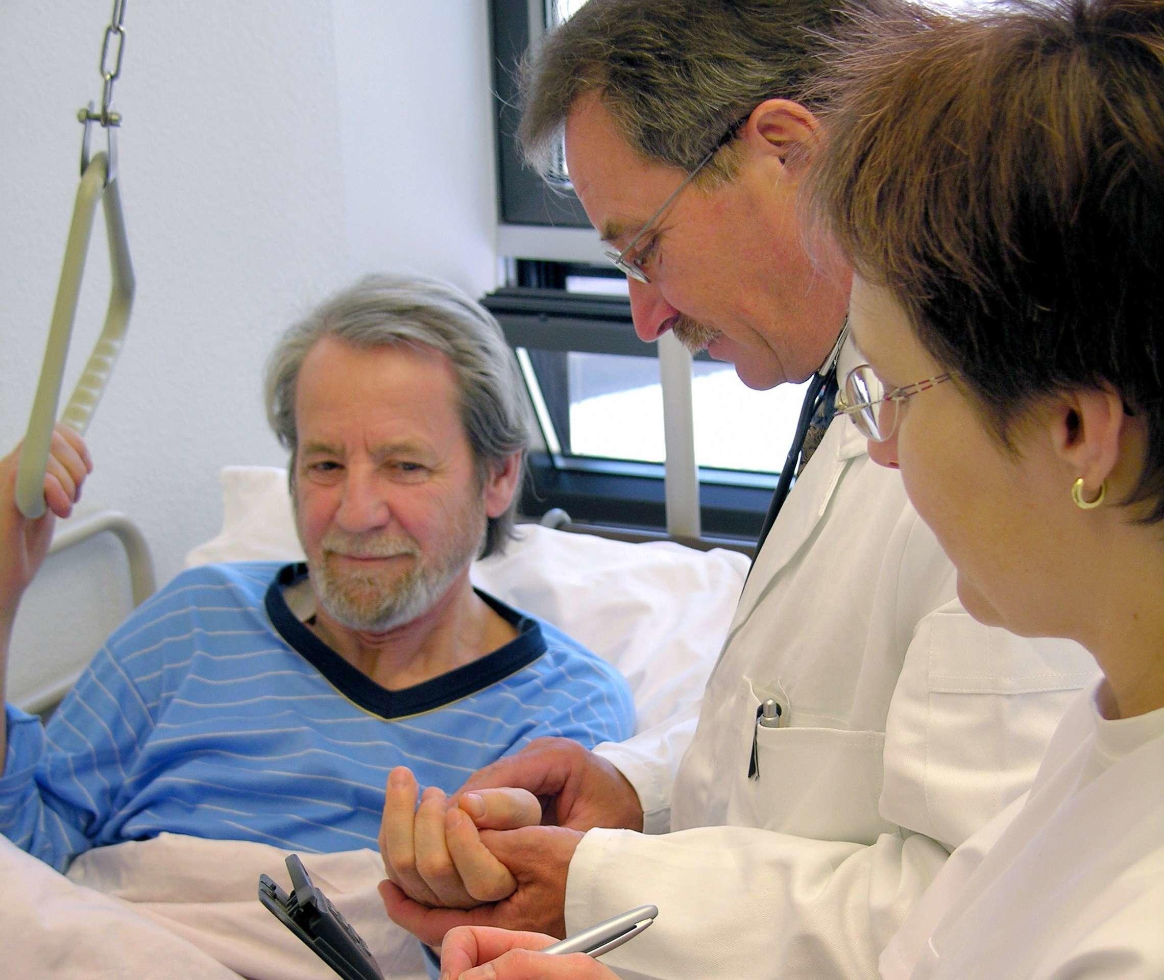 Transplantierter im Krankenhausbett spricht mit Ärzten