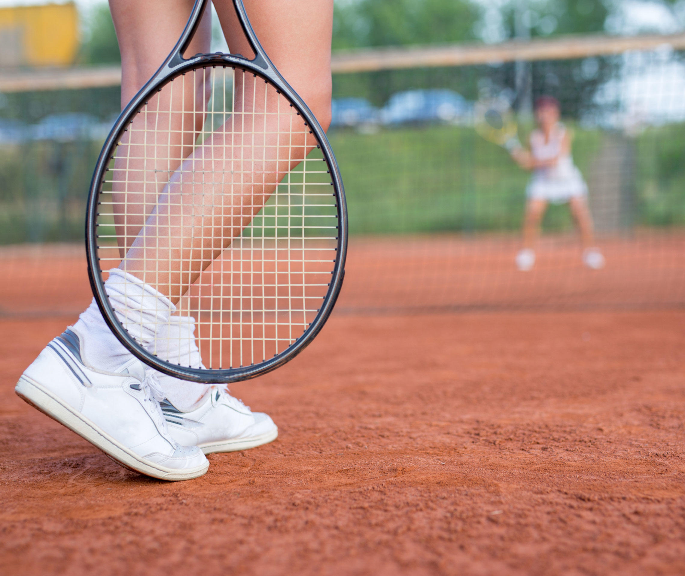 Tennisspielerin mit Tennisschläger auf dem Tennisplatz vor dem Netz.