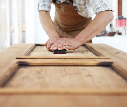 Handwerker schleift Holz.