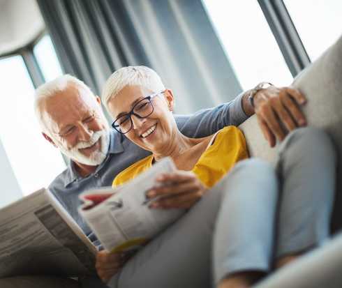 Ein Ehepaar sitzt gemeinsam auf dem Sofa und schaut sich Informationsbroschüren an