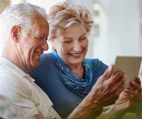 Ein aelteres Ehepaar schaut sich Informationen auf einem Tablet an