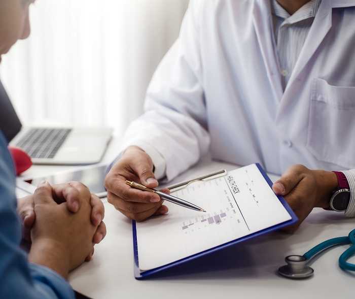 Ein Arzt zeigt seinem Patienten etwas auf einem Klemmbrett