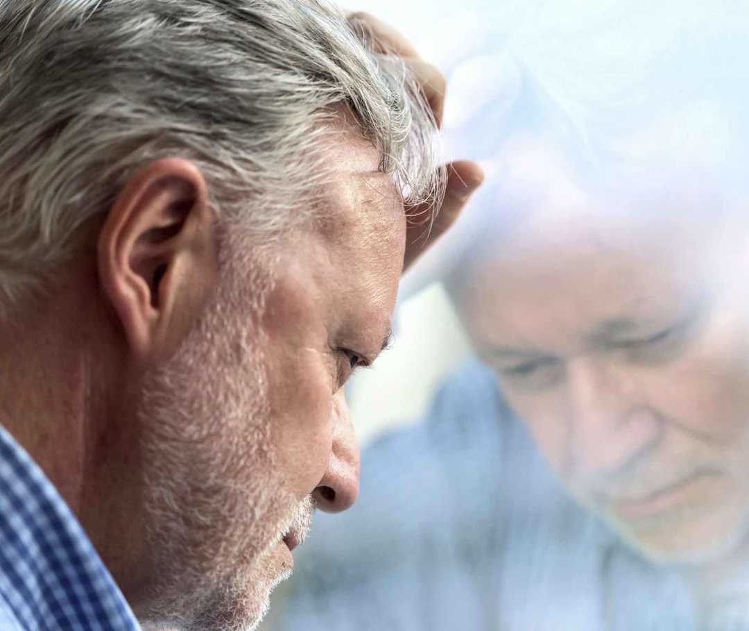 Nachdenklicher Mann lehnt an einer Glasscheibe