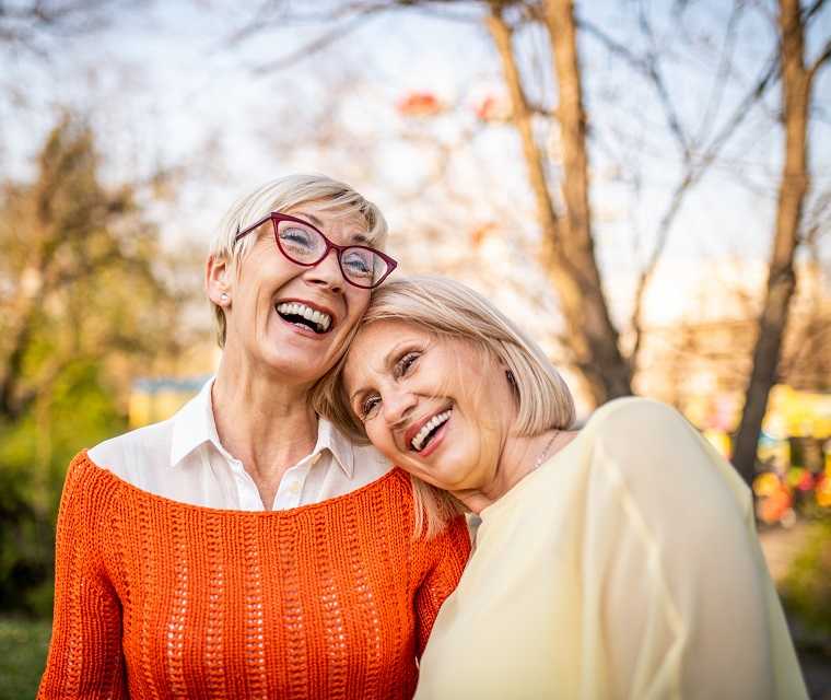 Zwei Frauen liegen sich in den Armen und lachen herzlich