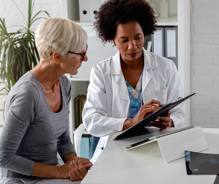 Junge Ärztin erklärt einer Dame vorliegende Unterlagen
