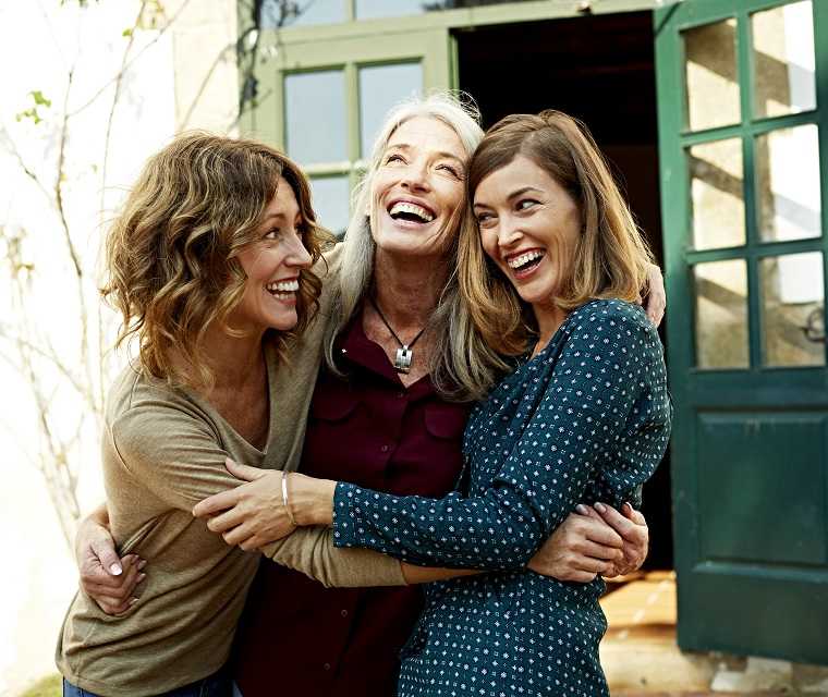 Drei lachende Frauen umarmen sich und genießen das Leben